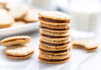 A stack of Brussels cookies with a glass of milk nearby