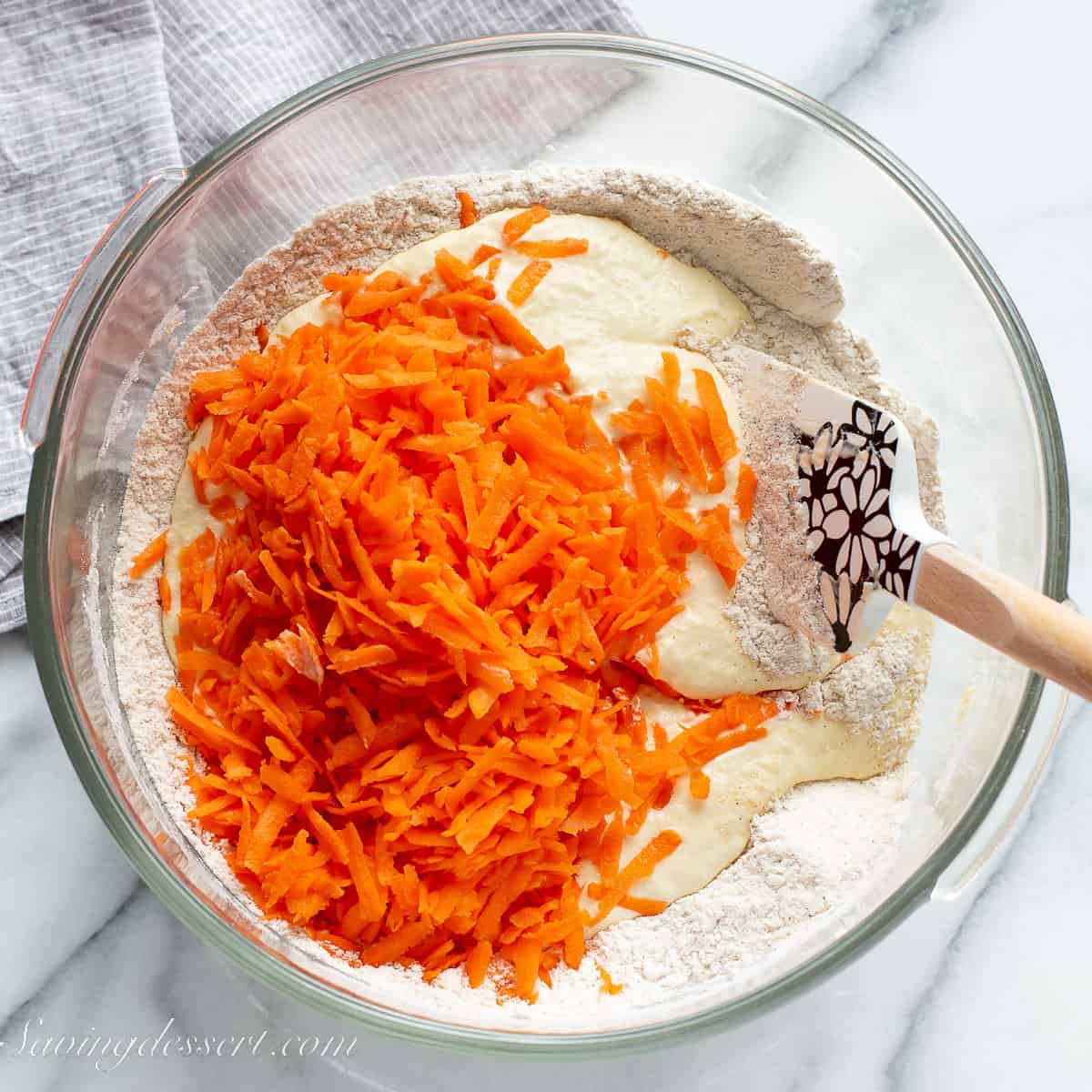 a bowl of muffin batter with shredded carrots