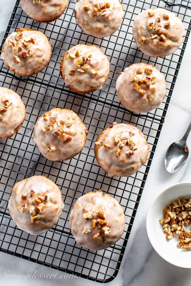 overhead view of a cooling rack with carrot cake muffins topped with chopped pecans