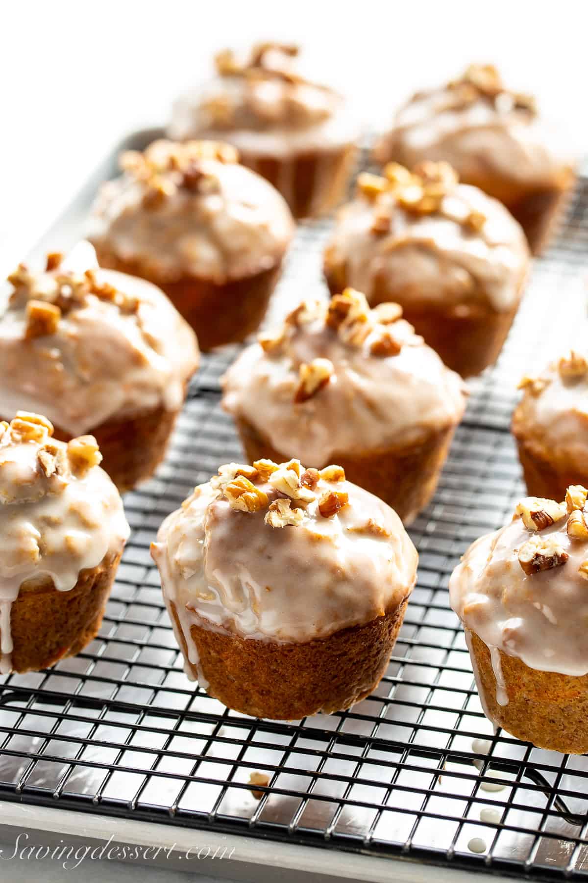 carrot cake muffins topped with a glaze and chopped pecans