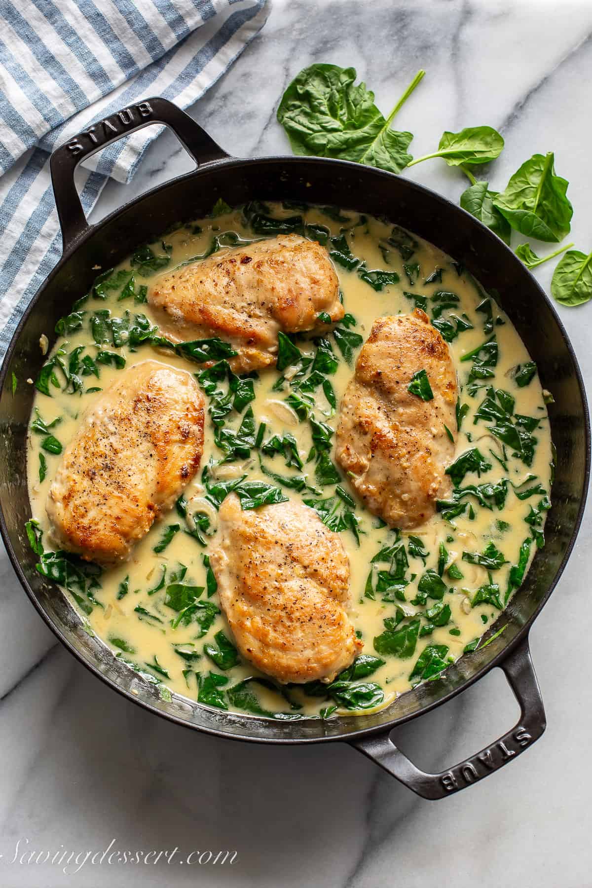 A skillet filled with chicken breasts in a spinach cream sauce
