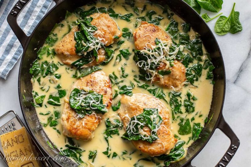 a skillet filled with chicken Florentine topped with Parmesan