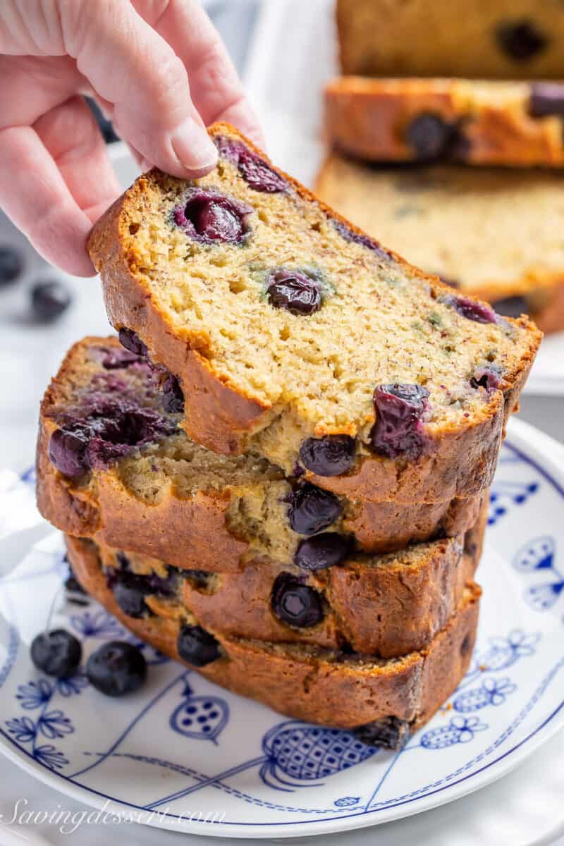 a stack of blueberry banana bread slices with the top being pickup up