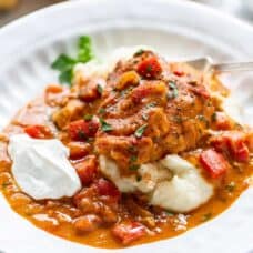 side view of a bowl filled with chicken paprikash over mashed potatoes