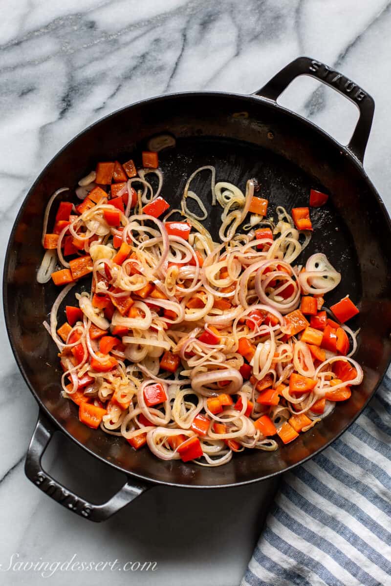 a skillet filled with diced red bell pepper and shallots