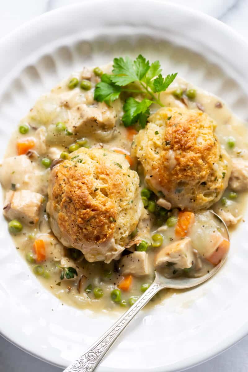 a bowl filled with chicken pot pie with golden brown herb biscuits on top