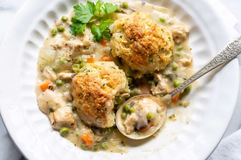 an overhead view of a bowl of chicken pot pie with herb biscuits on top