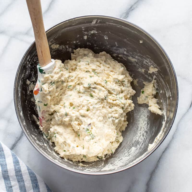 a mixing bowl filled with herb biscuit dough