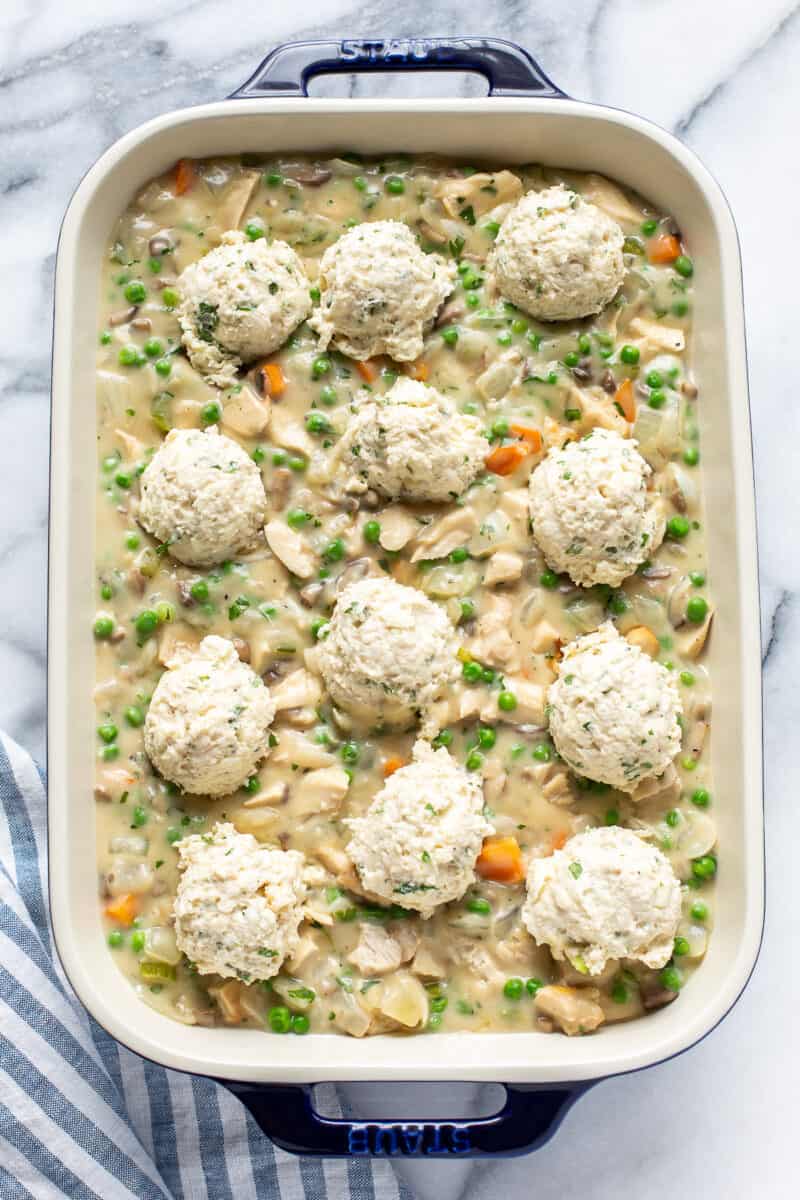 A casserole pan filled with chicken pot pie filling topped with mounds of biscuit dough