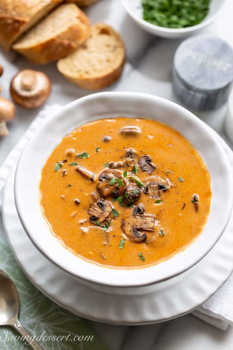 Overhead view of a bowl of Hungarian Mushroom Soup with sliced bread and parsley in the background