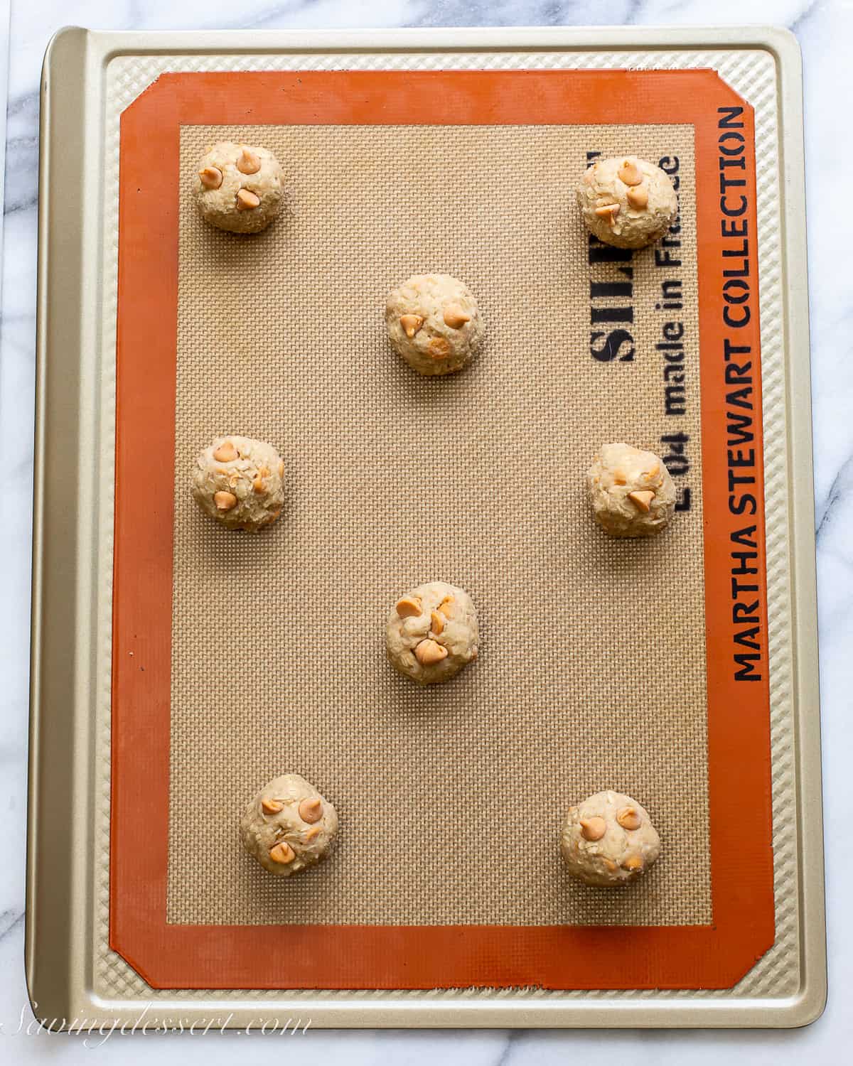cookie dough balls on a silpat mat ready to go in the oven