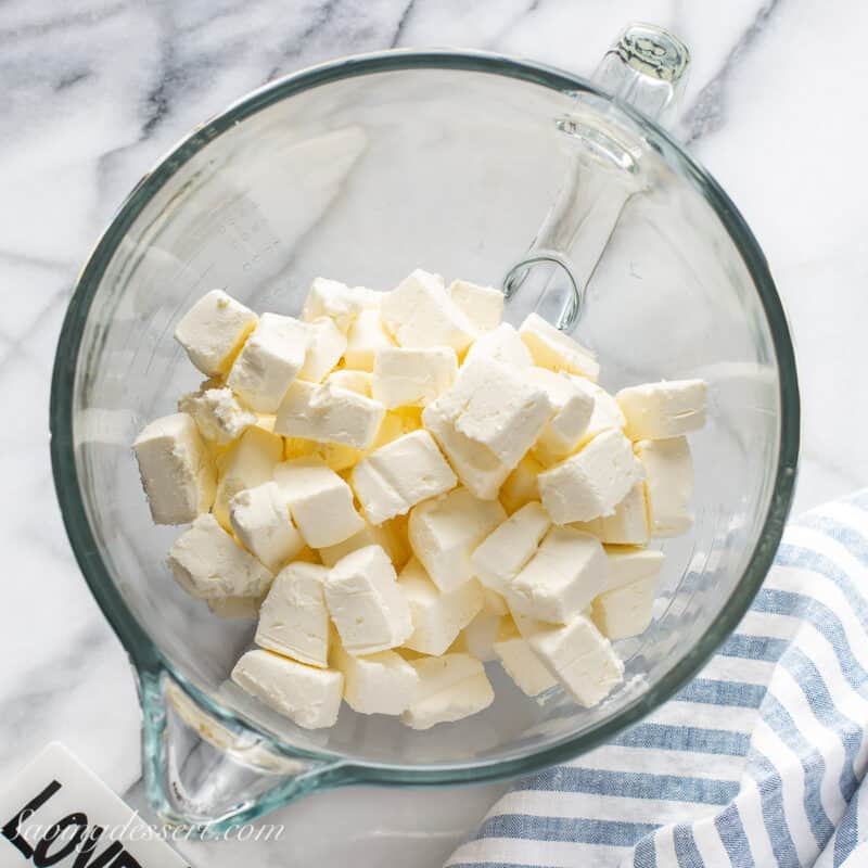 overhead view of a mixing bowl filled with chunks of cream cheese