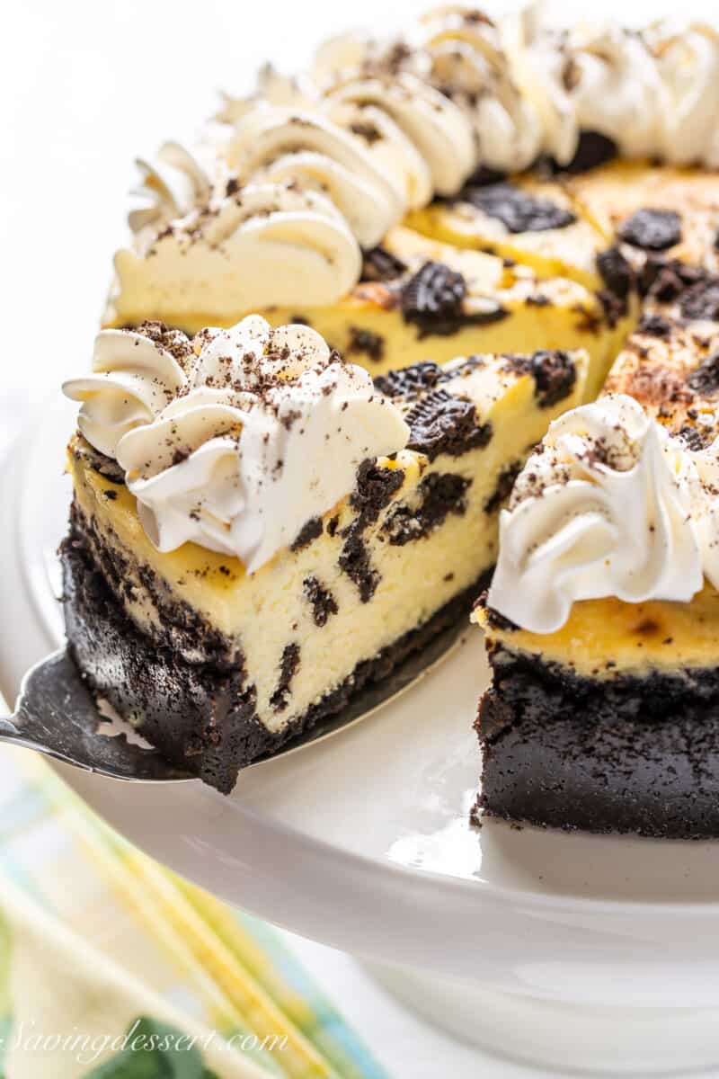 a slice of oreo cheesecake being taken from a cake stand