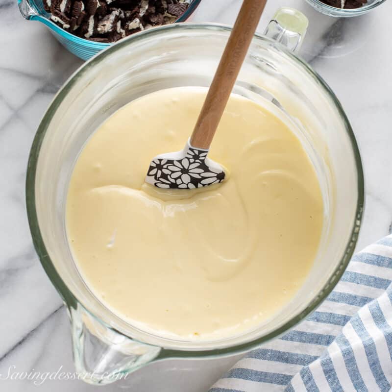 A bowl of cheesecake batter with a spatula