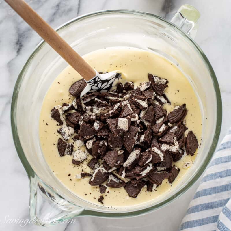 a mixing bowl filled with cheesecake batter and chopped Oreo cookies