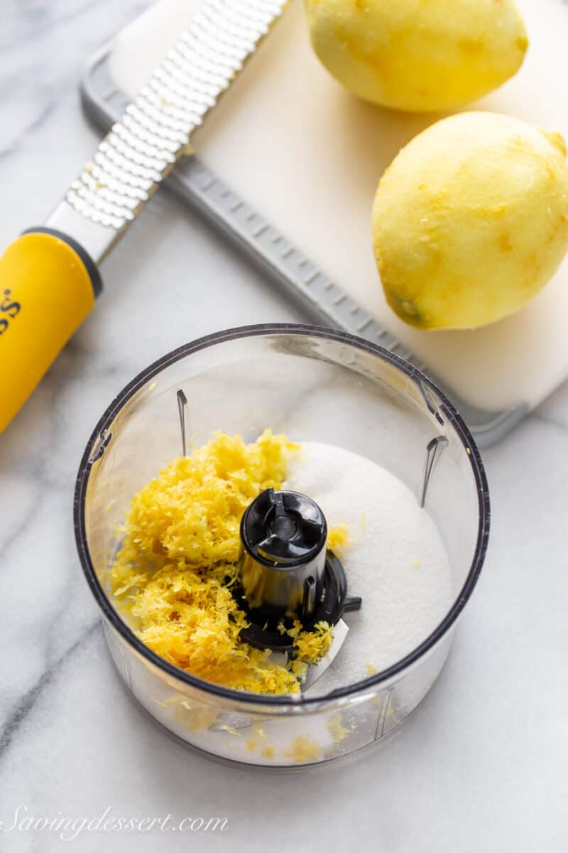 overhead view of a mini food processor filled with granulated sugar and lemon zest