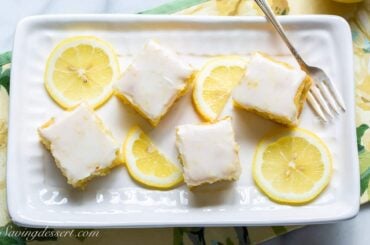 overhead view of a small platter with lemon brownies topped with lemon icing