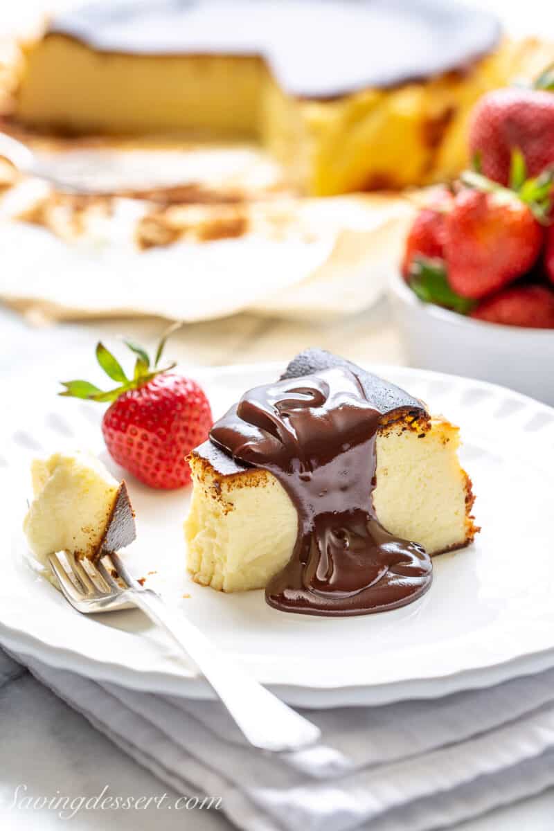 a piece of basque cheesecake on a plate topped with chocolate sauce and a fork