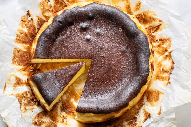 an overhead view of a sliced basque cheesecake on parchment paper