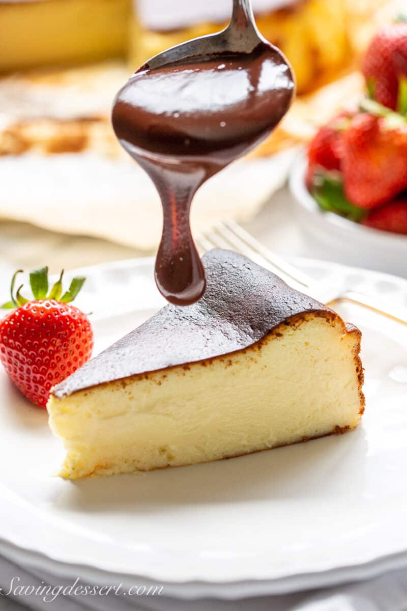 a slice of basque cheesecake about to be drizzled with chocolate sauce
