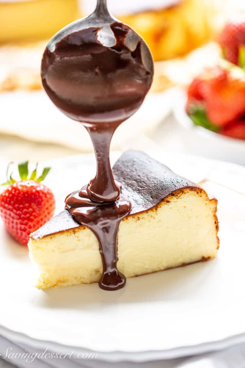 a piece of basque cheesecake being drizzled with chocolate sauce