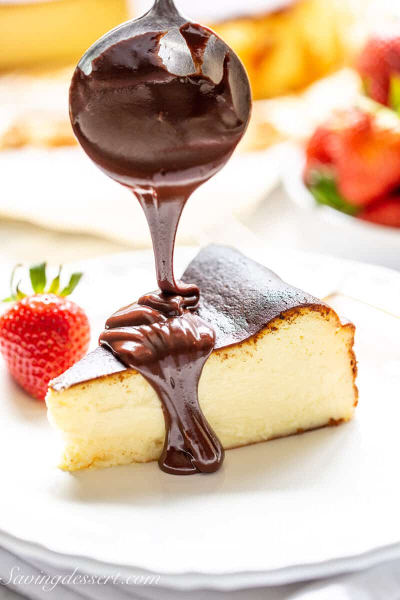 a piece of basque cheesecake being drizzled with chocolate sauce
