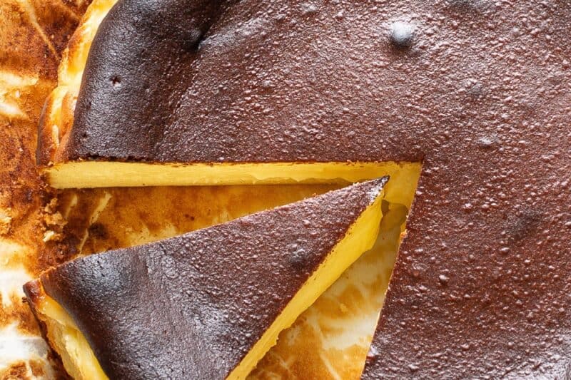 overhead view of a sliced basque cheesecake with a deep dark top crust and creamy middle