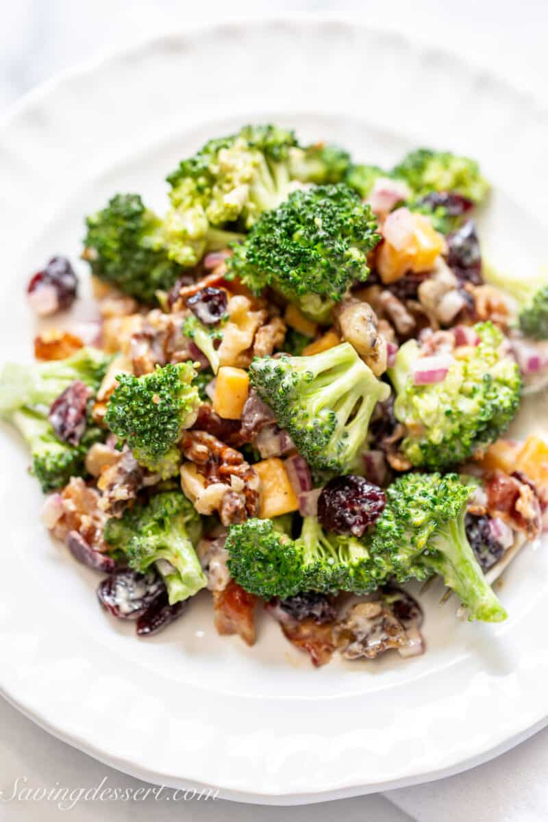 a plate filled with broccoli salad with raisins, cheese and bacon