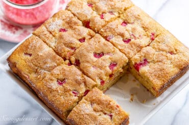 overhead shot of a square rhubarb cake cut into 9 pieces with one missing