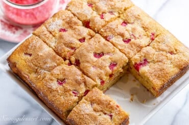 overhead shot of a square rhubarb cake cut into 9 pieces with one missing