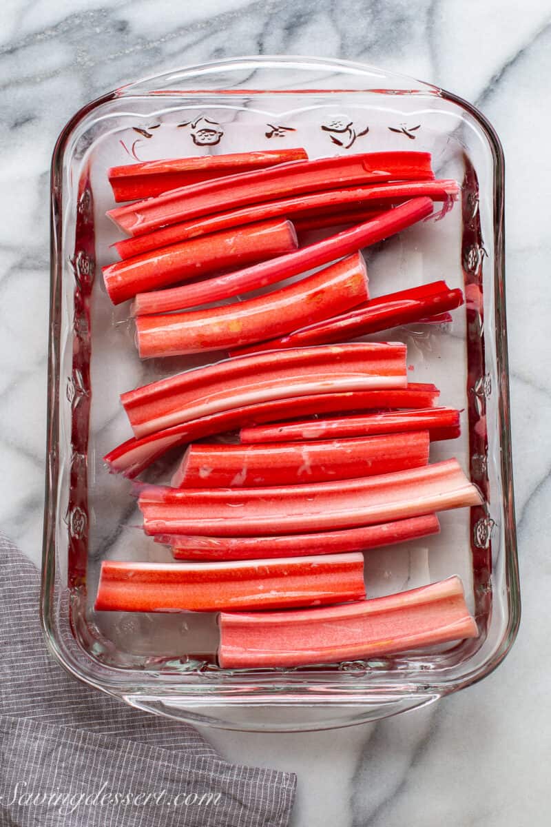stalks of rhubarb soaking in a glass casserole dish filled with cold water