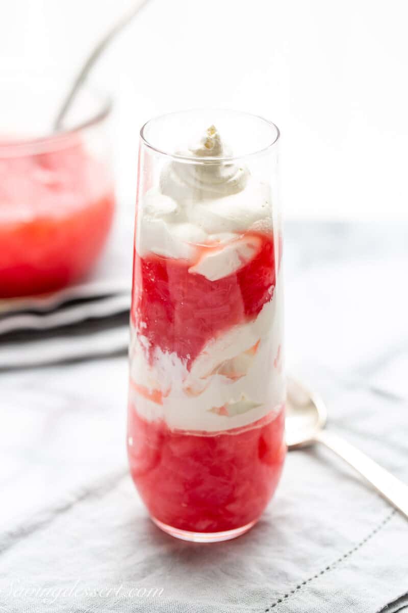 A tall skinny glass layered with rhubarb sauce and whipped cream