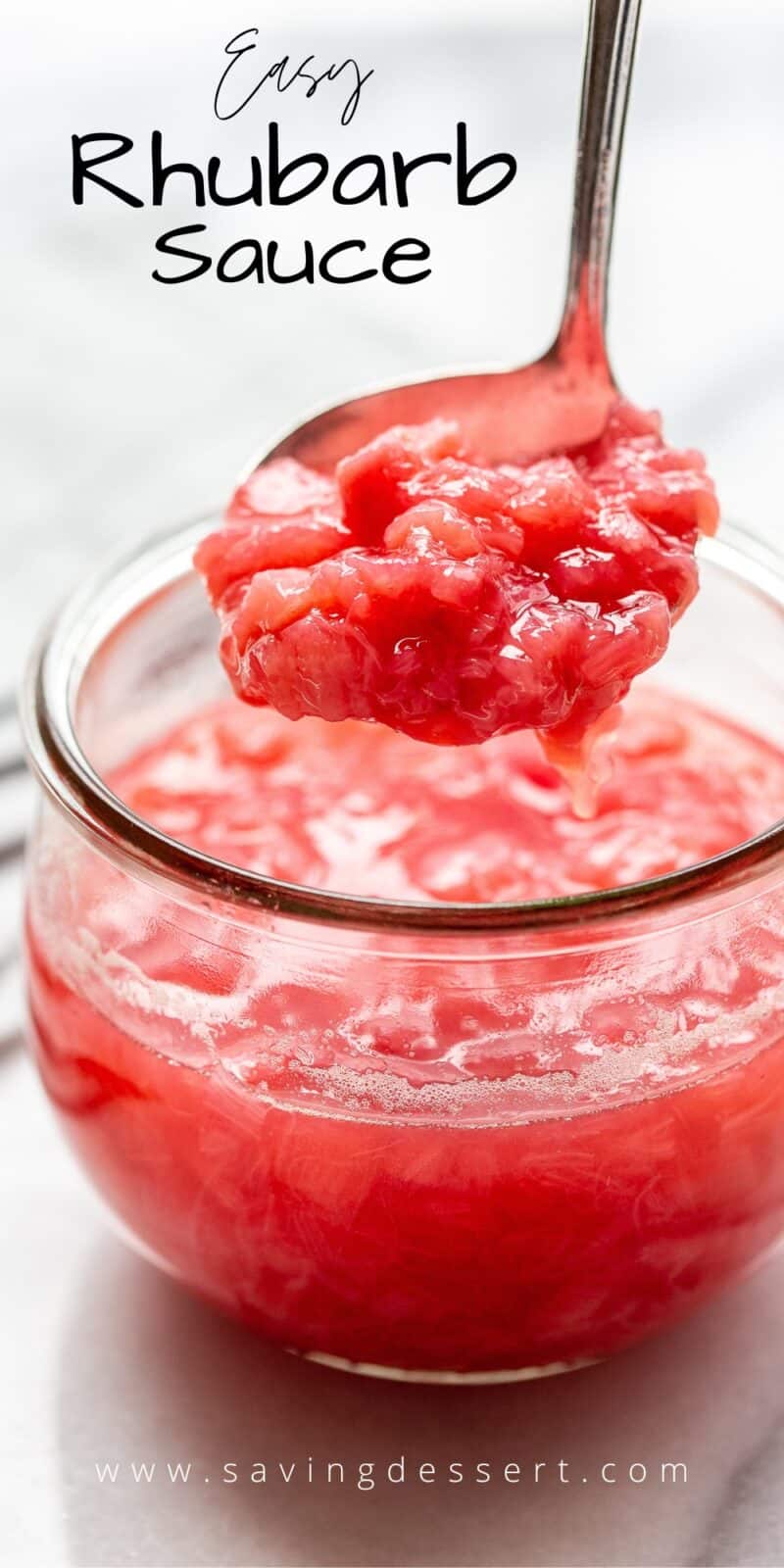 A closeup of a wide mouth jar filled with chunky rhubarb sauce with some being scooped out
