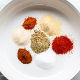 a large white bowl with individual scoops of seasonings to be blended together