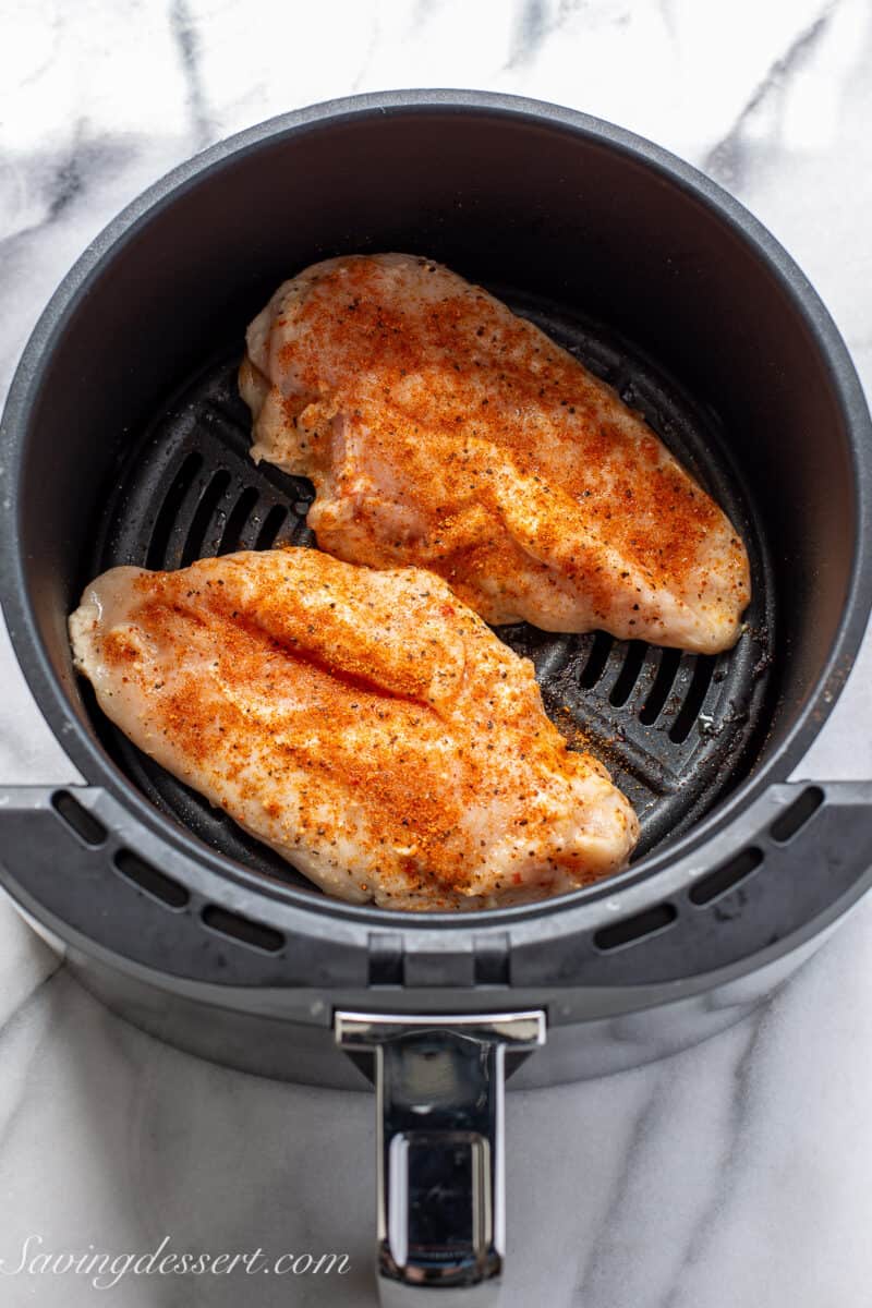 two chicken breasts in an air fryer basket