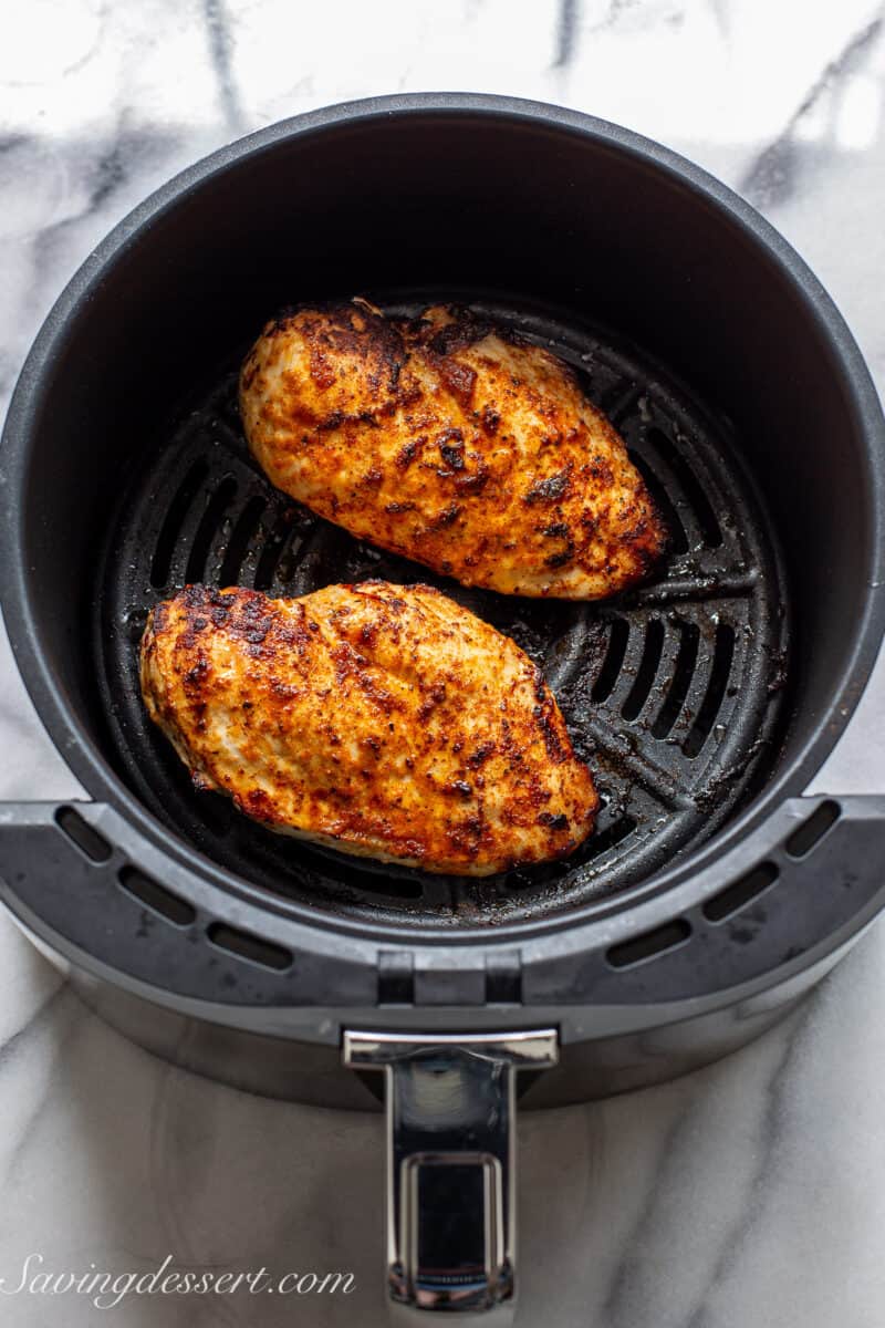 cooked chicken breasts in an air fryer basket