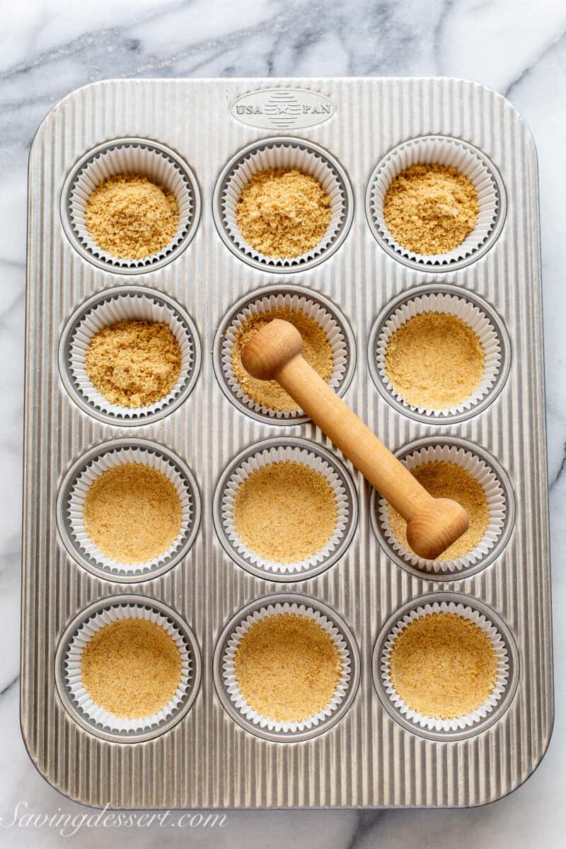 graham cracker crumbs being packed into a muffin tin