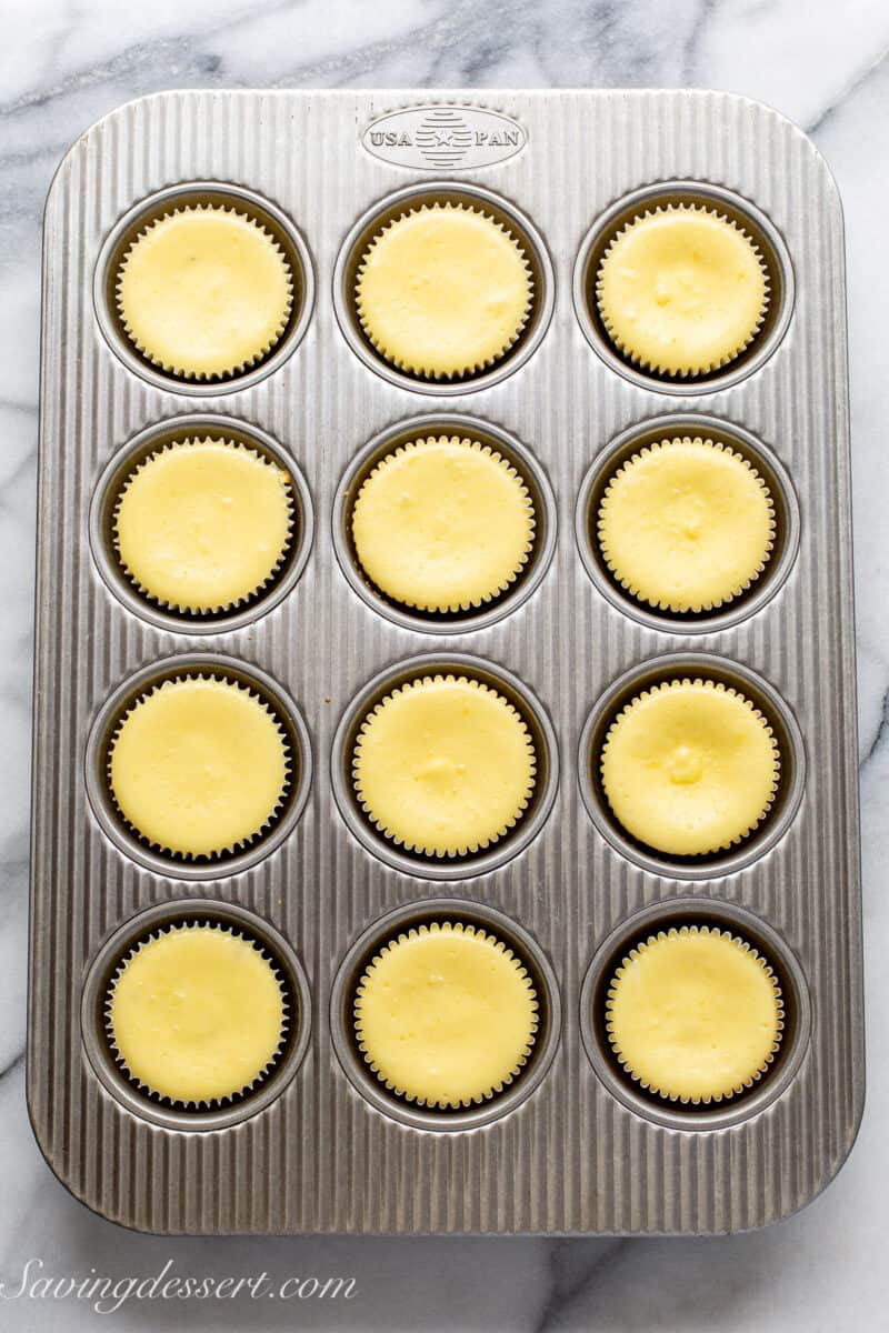 a muffin tin filled with baked mini cheesecakes