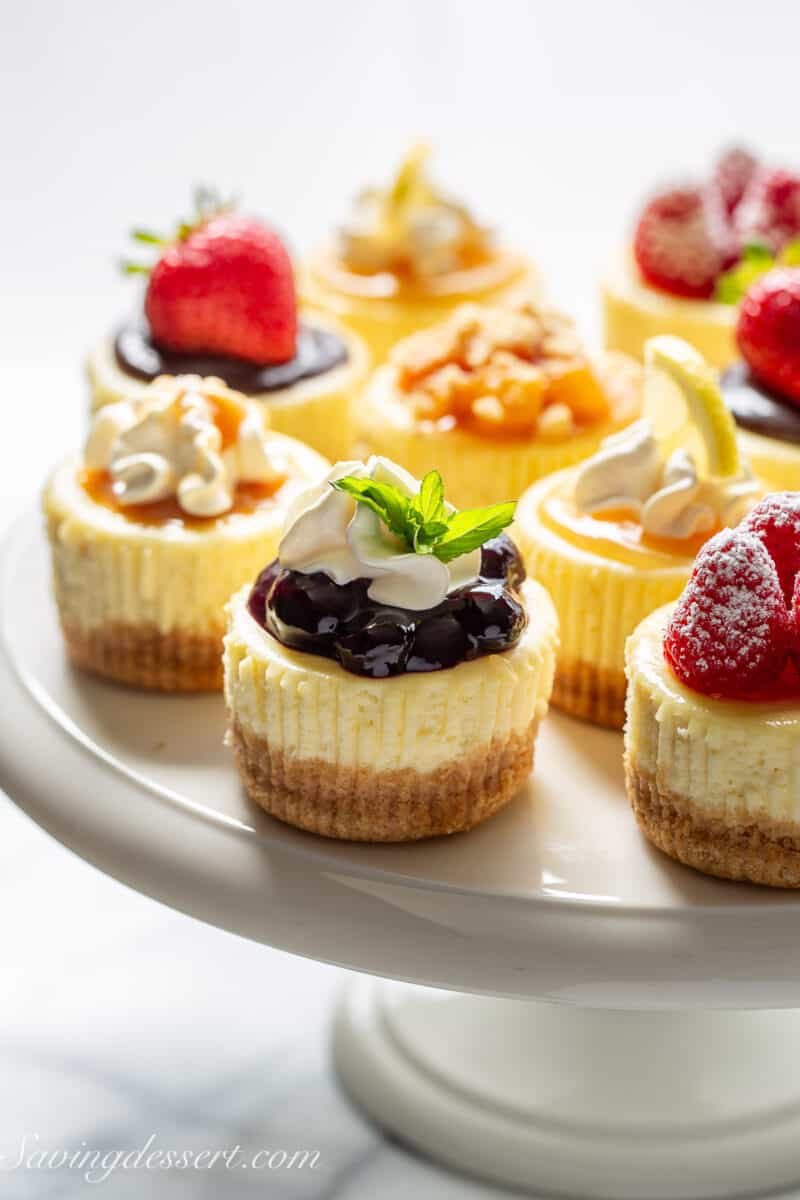 A platter filled with mini cheesecakes topped with various toppings