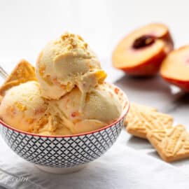 a bowl of homemade peach ice cream with shortbread cookies on the side