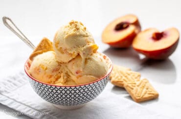 a bowl of homemade peach ice cream with shortbread cookies on the side