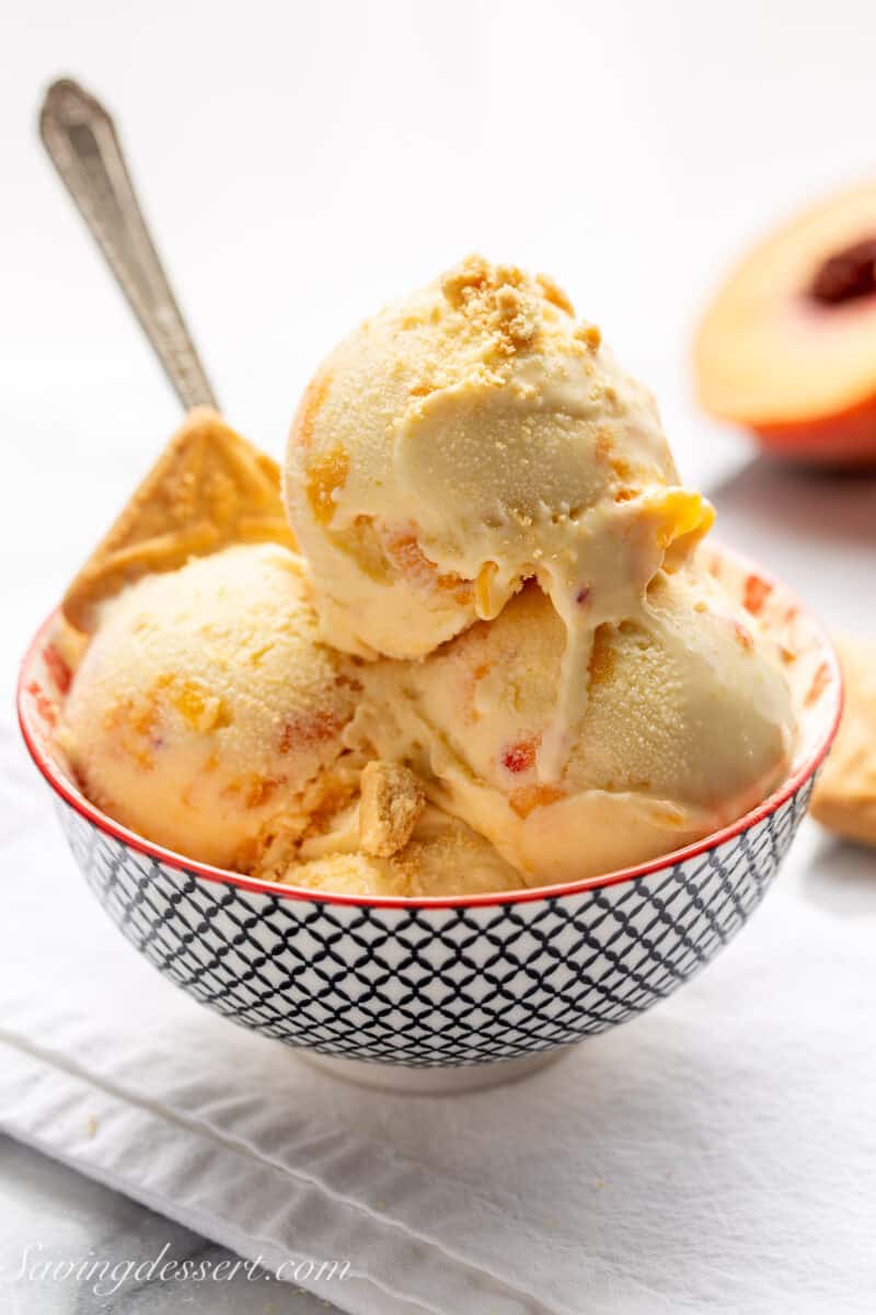 A bowl of peach ice cream with a spoon and shortbread cookies