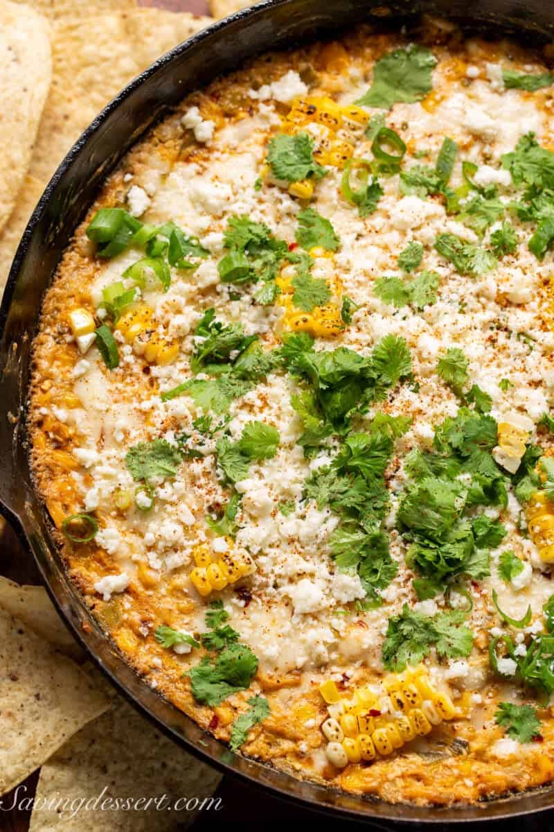 closeup of hot Mexican corn dip in a cast iron skillet with cotija cheese and cilantro on top