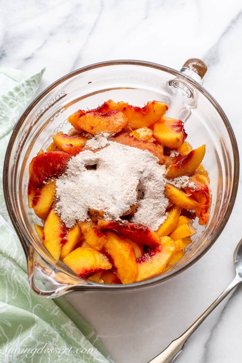 A bowl of sliced peaches with a cinnamon sugar mixture poured over the top.