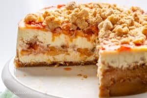 Close up of a sliced peach cheesecake with a cinnamon crumble topping.
