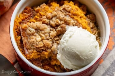 A bowl of pumpkin crisp with a scoop of vanilla ice cream.
