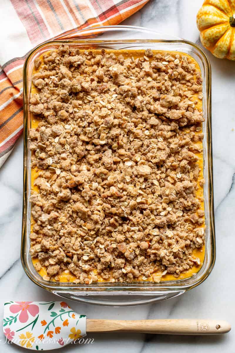 A large baking pan filled with a pumpkin mixture topped with a crisp topping of nuts and oats.