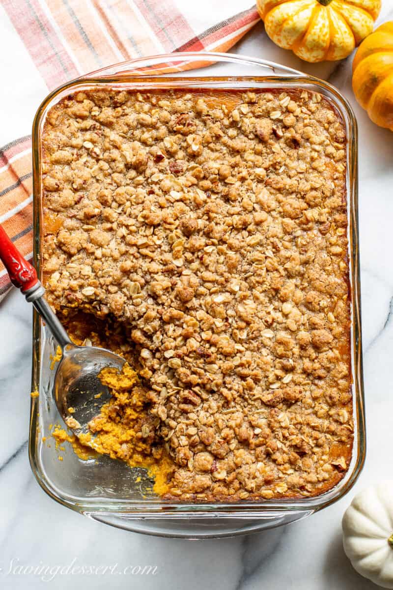 An overhead photo of a pan filled with pumpkin crisp with a spoonful removed.