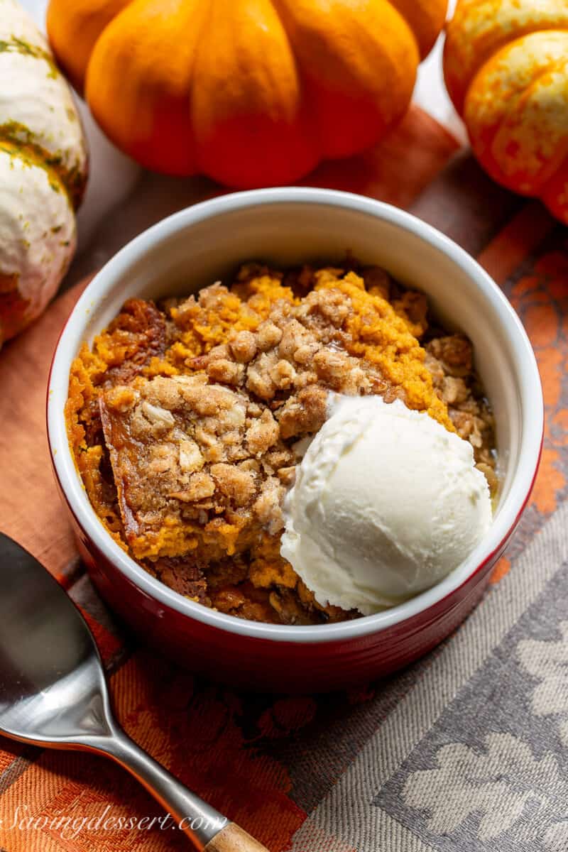 Overhead shot of a small serving bowl filled with pumpkin crisp with a scoop of vanilla ice cream on top.