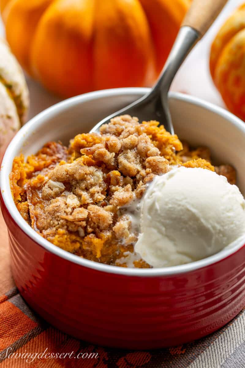 Closeup of a bowl of pumpkin crisp with a spoonful being scooped out.